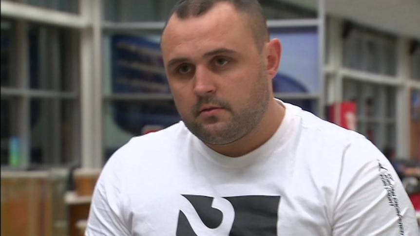 Kyle Pryde walking through the airport with a serious expression on his face.