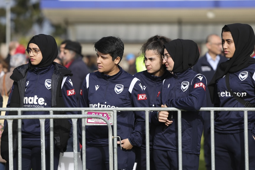 A football team dressed in dark, navy blue jerseys 