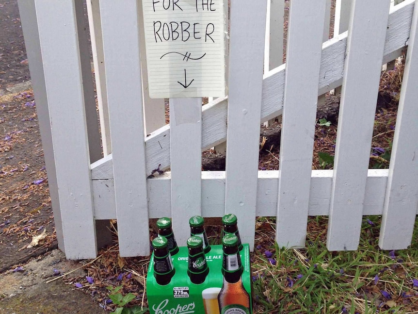 A six pack of beer sits by a fence in West Hobart