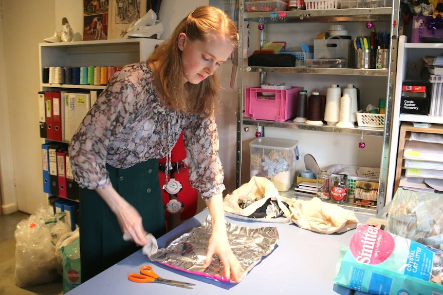 A woman lays a chips packet flat on a table.