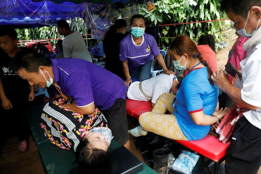 Volunteers give massages to family members near Tham Luang cave complex.