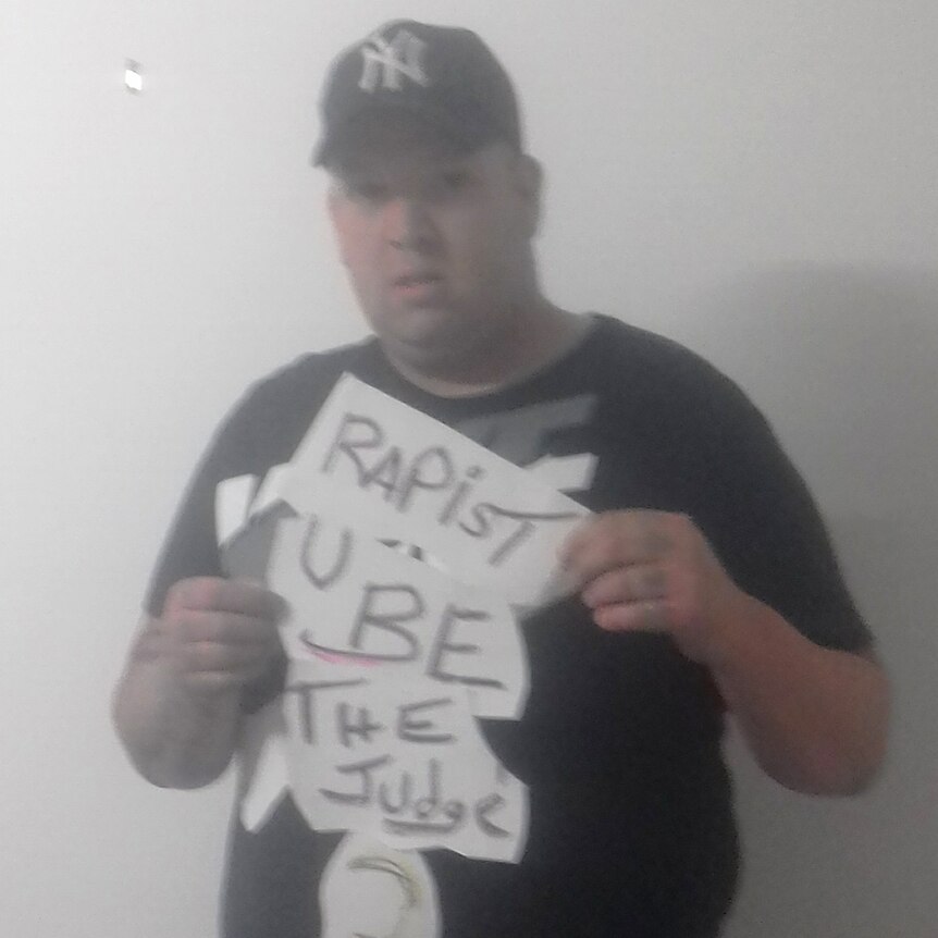 A picture of convicted rapist Damien Kennedy holding a sign