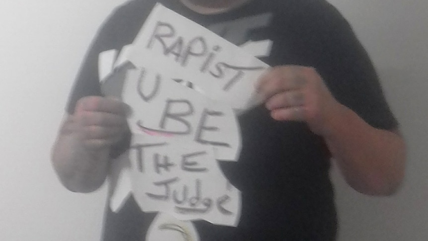 A picture of convicted rapist Damien Kennedy holding a sign