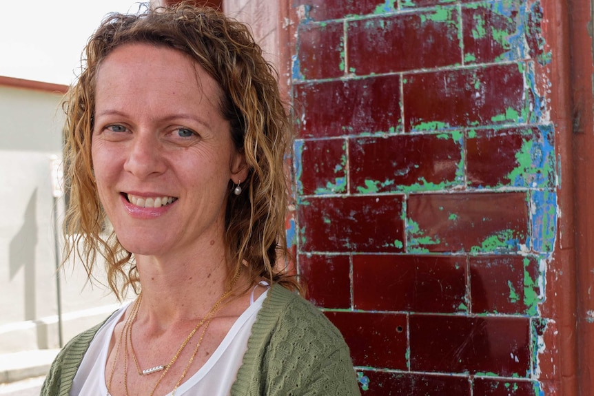 Sydney primary school chaplain Megan Harris stands next to red brick building.