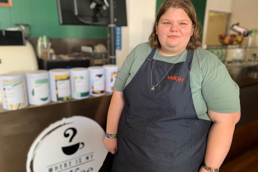 Trainee Bianca Paola stands in front of a counter in a coffee shop.