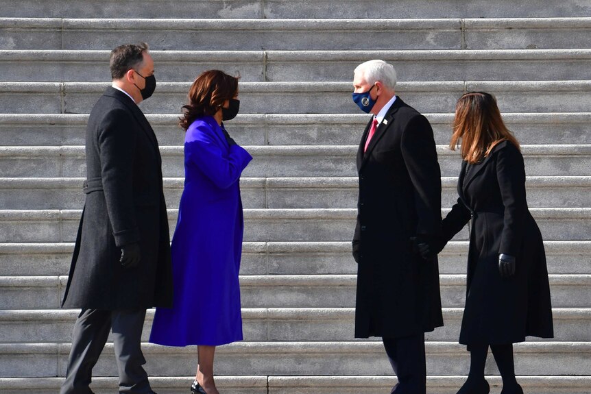 Kamala Harris,  Douglas Emhoff stand to left of photo at bottom of concrete steps, Mike Pence and Karen Pence stand on right.