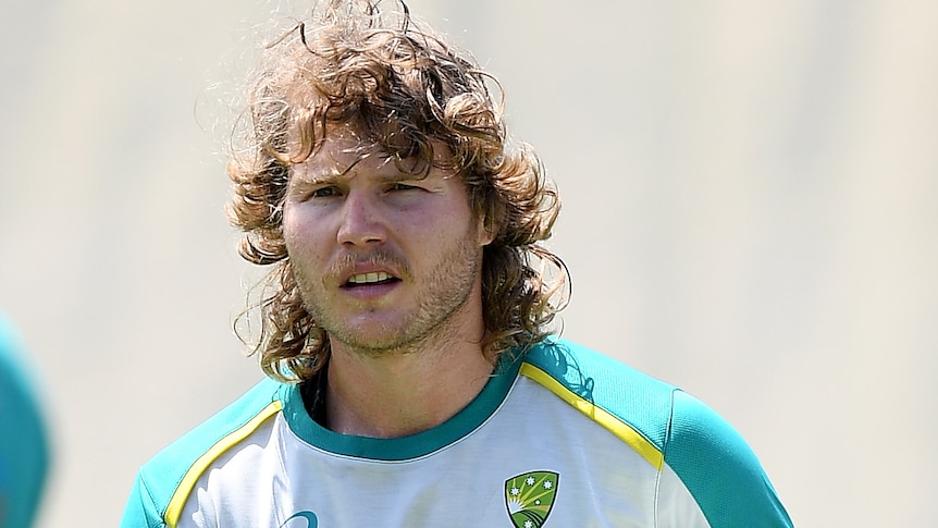 An Australian male Test cricketer holds his helmet at a batting net session in Sydney.