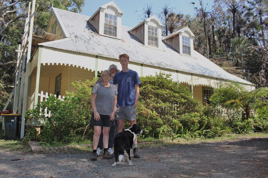 A family stand in front of a house.