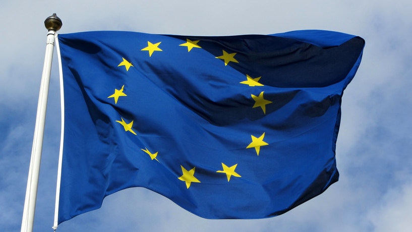 European Union flag against a cloudy blue sky.