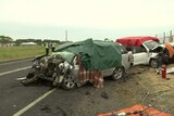 Two car wreckages on the side of a road