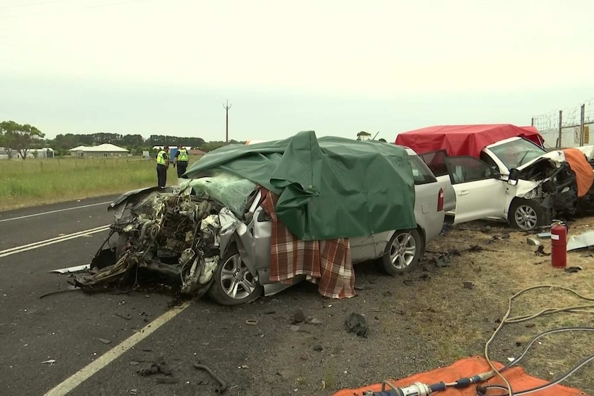 Two car wreckages on the side of a road