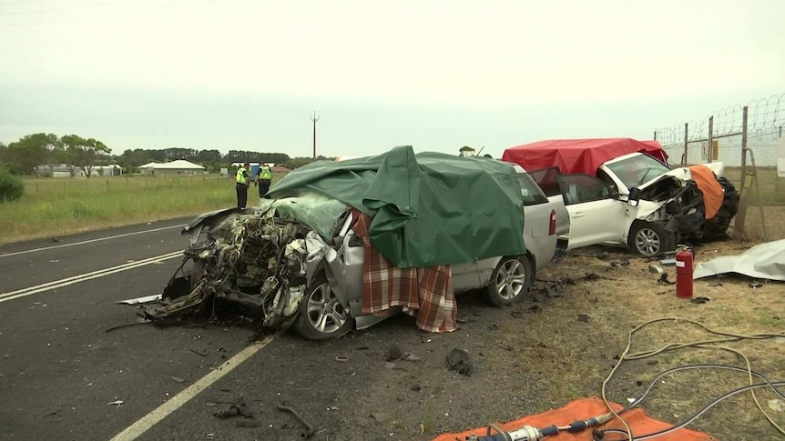 Two car wreckages on the side of a road