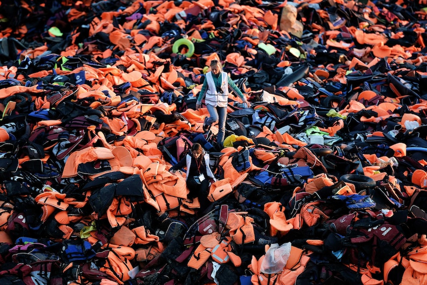 People walking on piles of lifejackets.