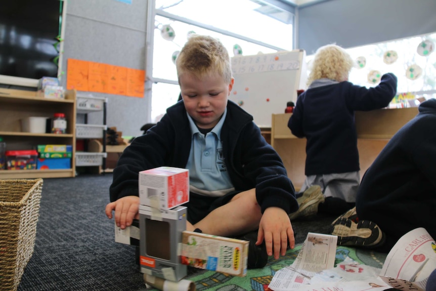 A kindergarten student making cardboard box construction play based learning June 2016