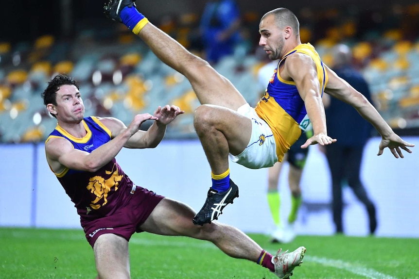 Dom Sheed flies through the air in an awkward position as Lachie Neale watches him, seemingly after pushing him