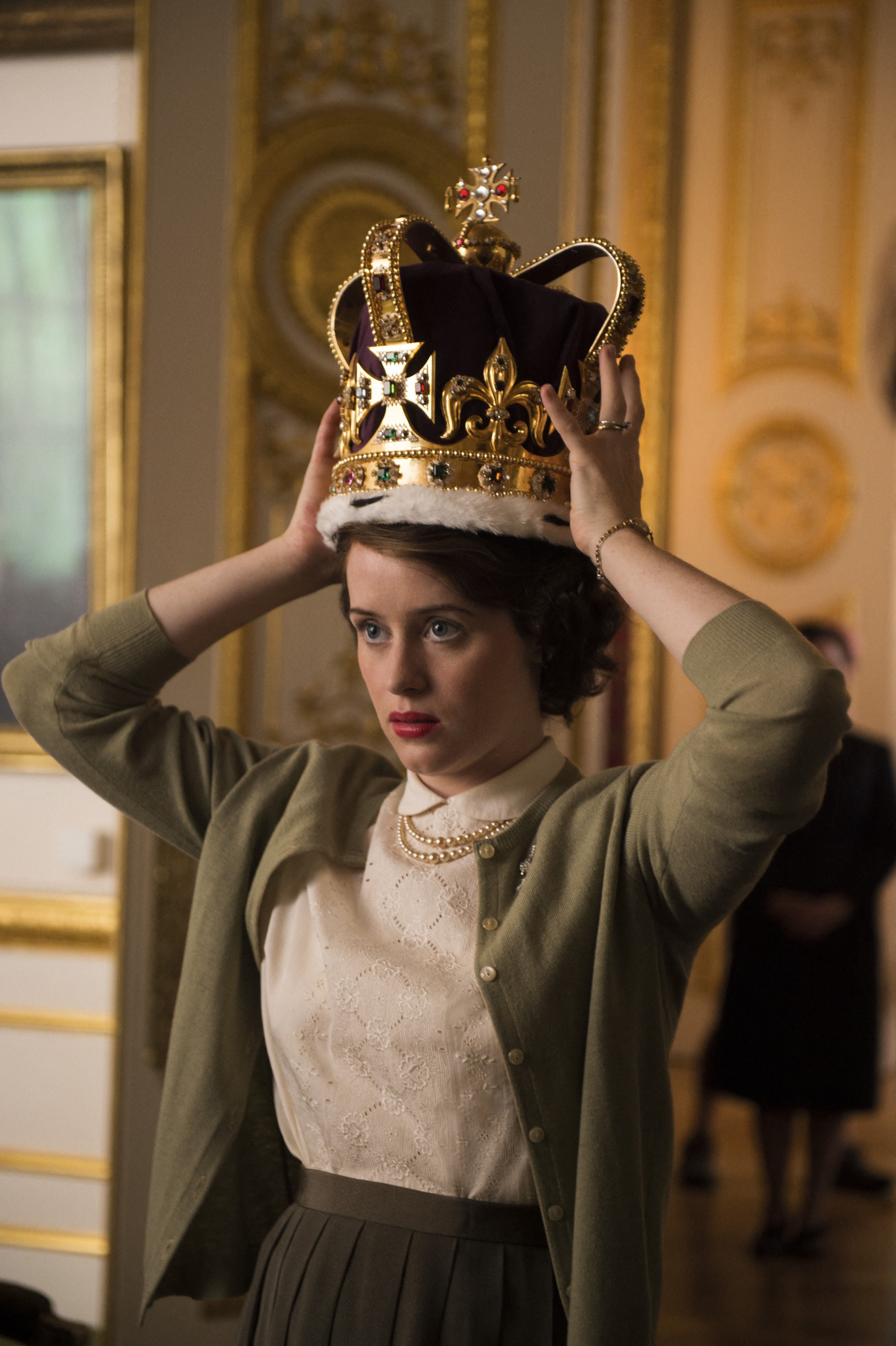 Foy places a gold crown on her head.