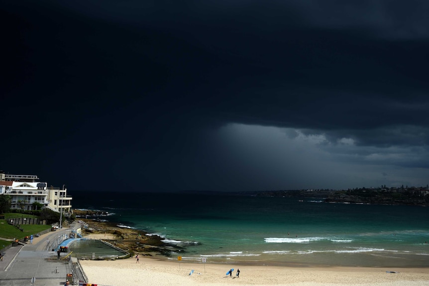 Surfers leave the water as storm clouds roll over Bondi Beach, Sydney November 13, 2015