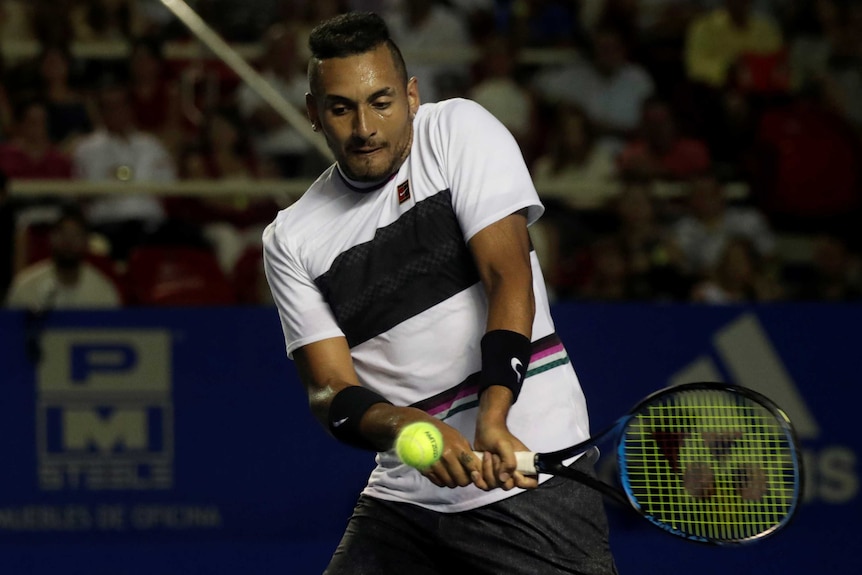 Nick Kyrgios looks down as he hits a double-fisted backhand with his tennis racquet.