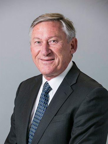 A man in a grey suit with grey hair against a grey background.