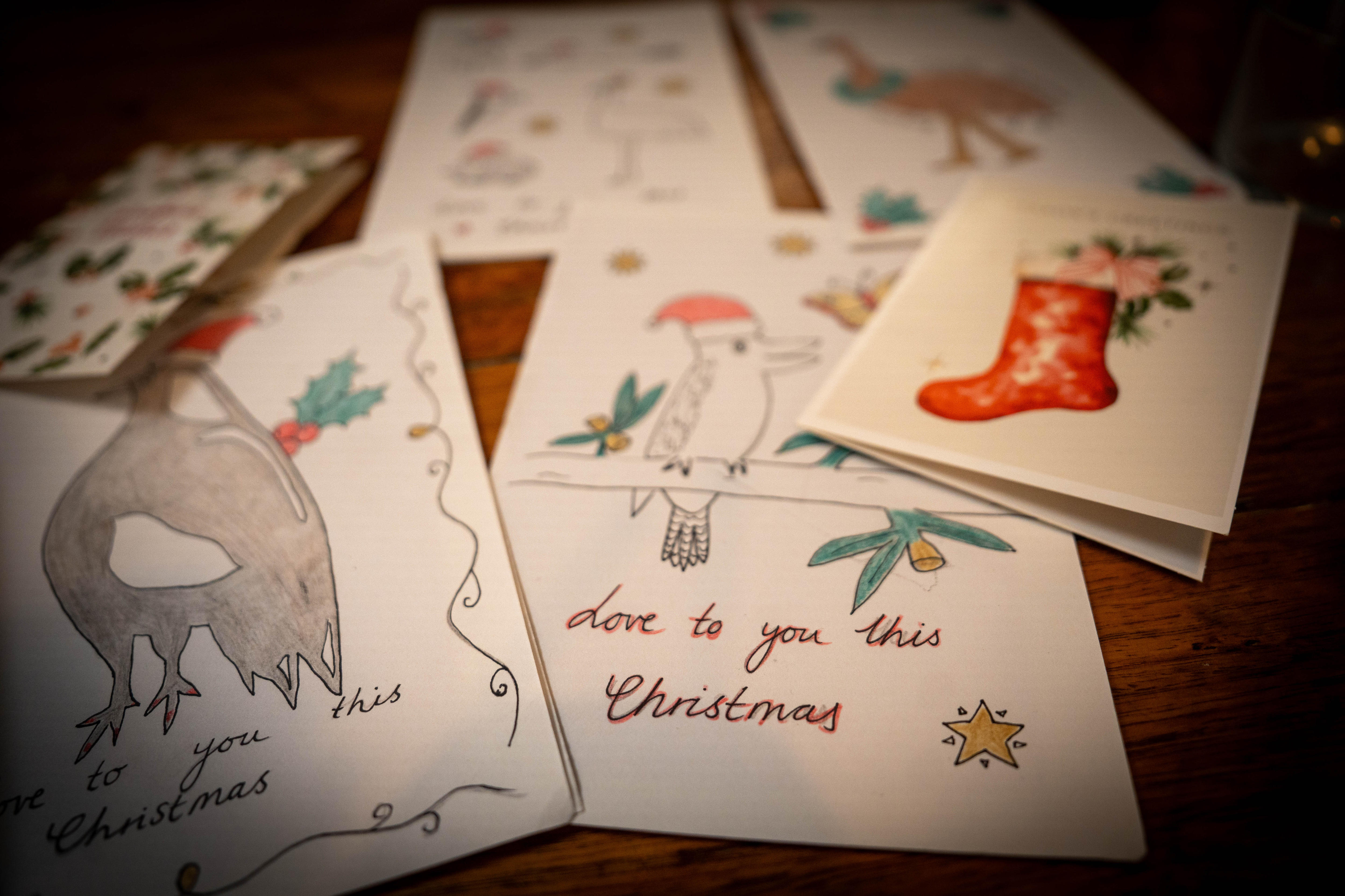 Tarjetas de Navidad dibujadas a mano con mensajes de felicitación esparcidos sobre una mesa