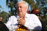Clive Palmer claps his hands and wears a white collared shirt at a rally in Canberra.