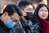 Travelers wear face masks as they walk outside of the Beijing Railway Station.