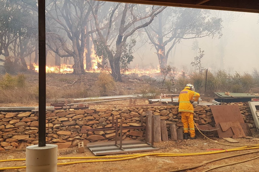 A fire comes close to a rock wall.