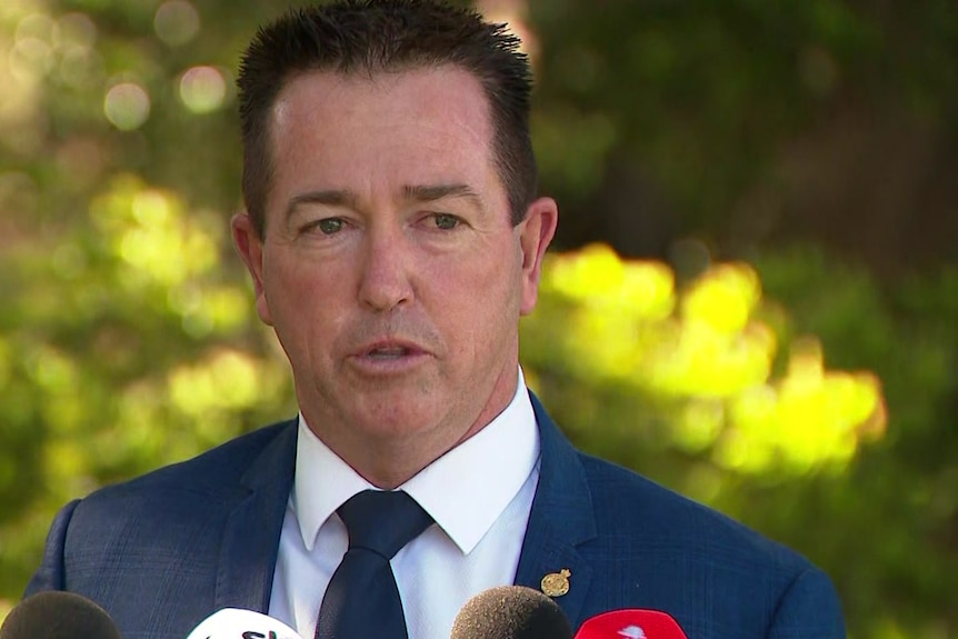 Paul Toole in a blue suit at a press conference.