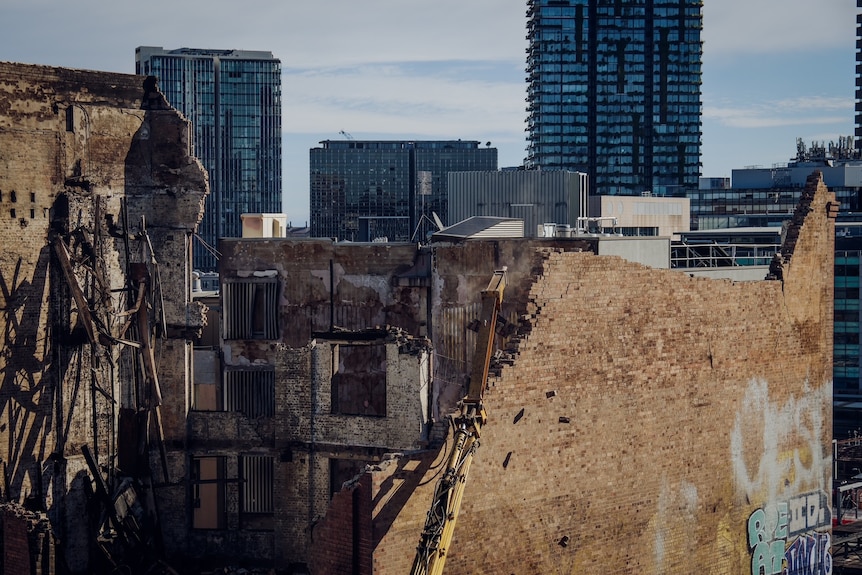 Crane knocking down brick wall 