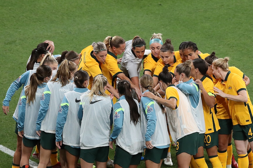Female soccer players standing in a huddle before a match