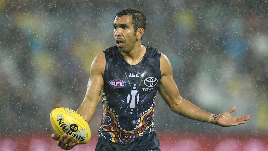 Eddie Betts plays AFL in pouring rain. He's wearing the Adelaide Crows' Indigenous heritage jersey.