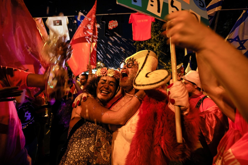 Supporters of Israel's new coalition government hug each other and celebrate