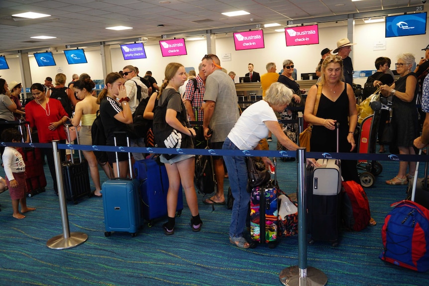 A group of travellers stand in line to check in at Darwin airport.