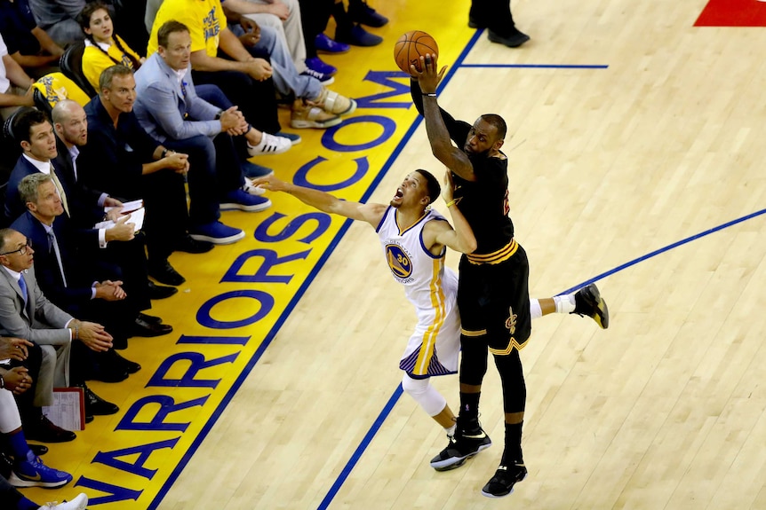 LeBron James keeps the ball away from Stephen Curry
