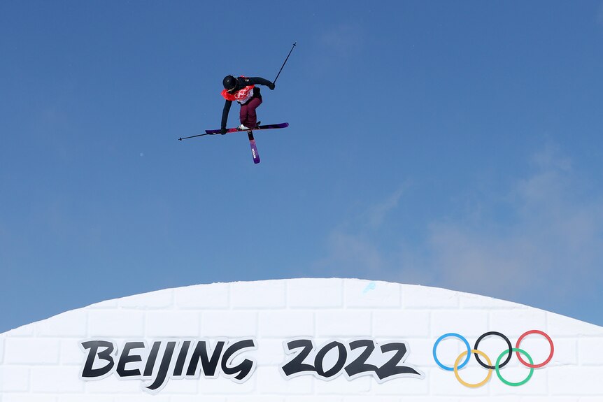 An Estonian female skier in the air during a slopestyle competition at the Beijing Winter Olympics.