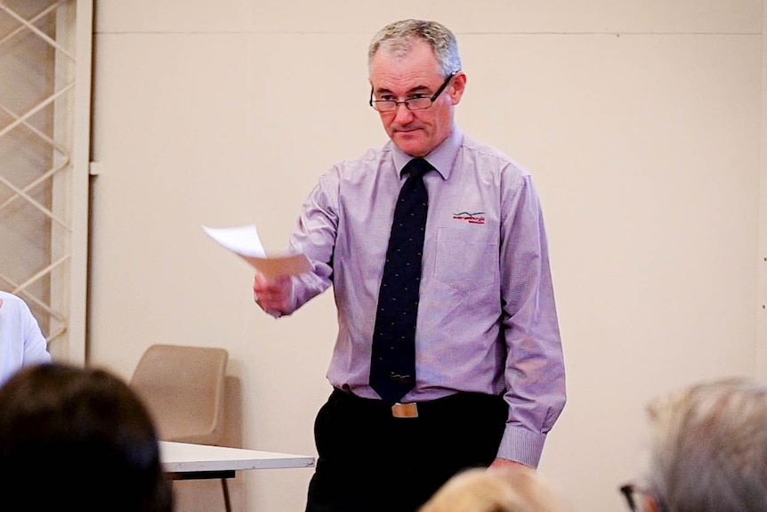 A man holding a stack of papers at a town hall meeting