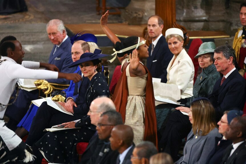 Two dancers are mid performance in the middle of an aisle between pews. Kate, William and Charles look on form the front row