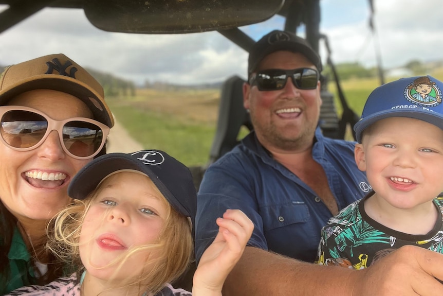 A family of four smile for a selfie in a tractor cabin.