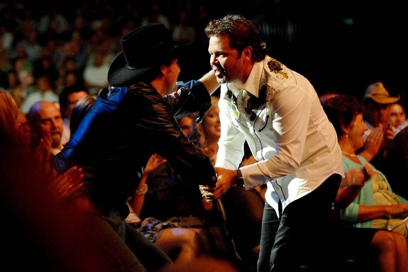 Troy Cassar-Daley leans in to shake the hand of Lee Kernaghan, who has his other hand on Cassar-Daley's shoulder.