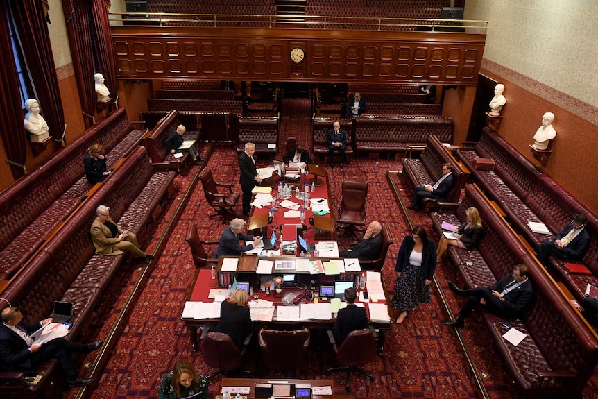 Several people sitting in a large room, seen from a distance