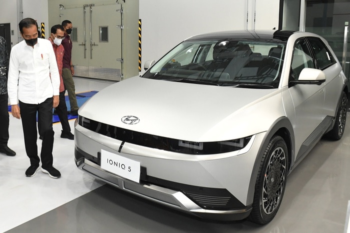 Indonesian president Joko Widodo standing next to an electric car.