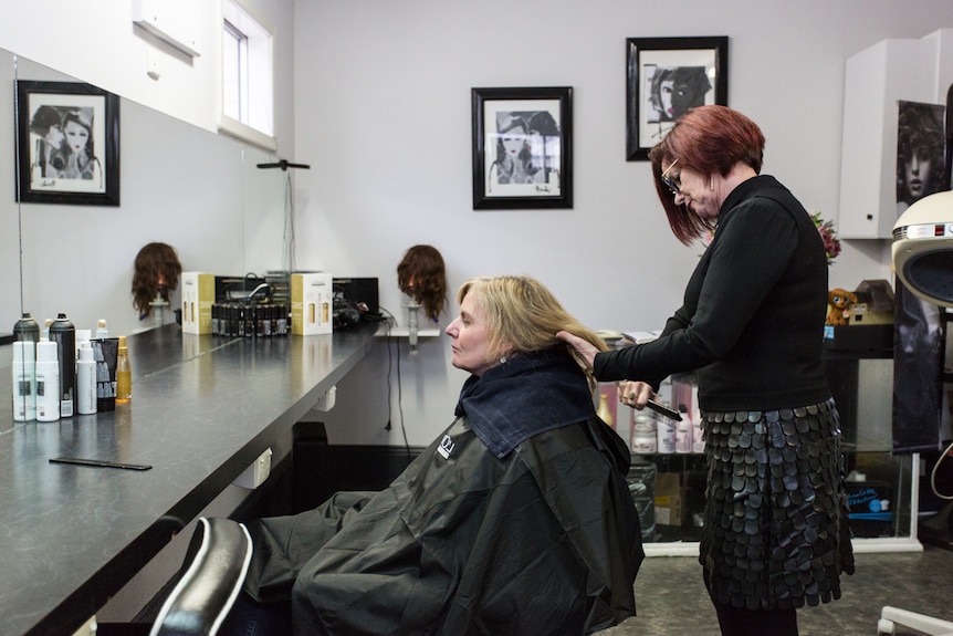 Hairdresser Gayle Emmett brushing the hair of her client.
