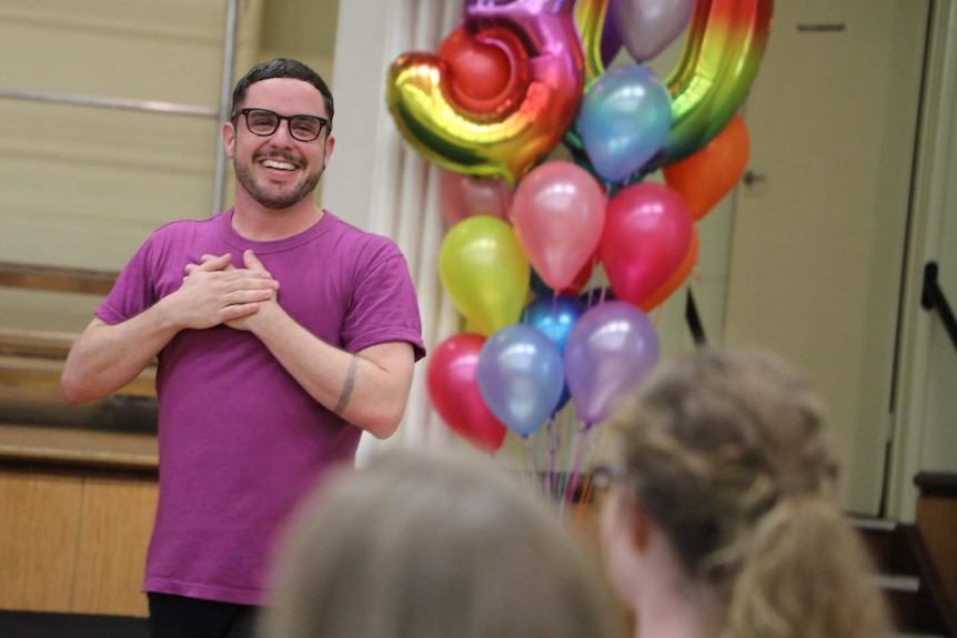 A man smiling with balloons in the background.