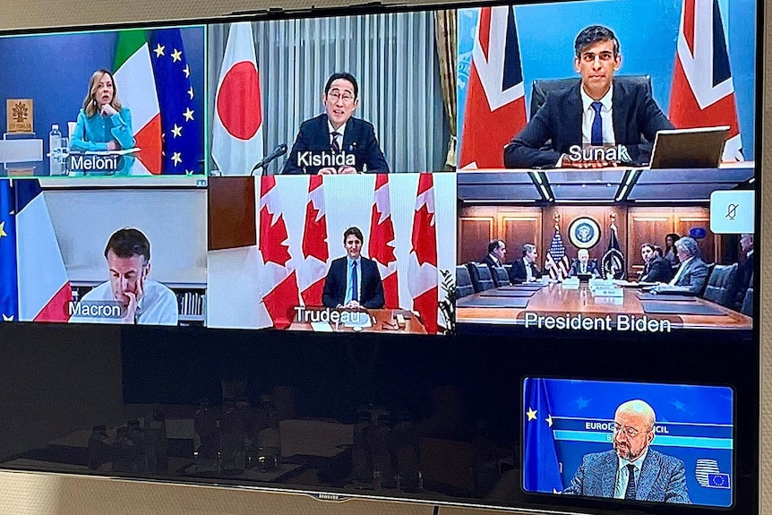 A television screen shows world leaders talking in an online meeting