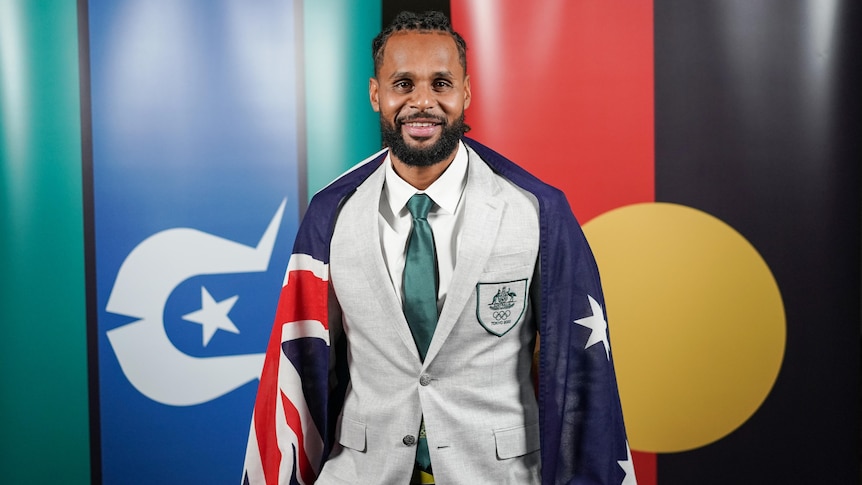 A male basketballer has the Australian flag over his shoulders.