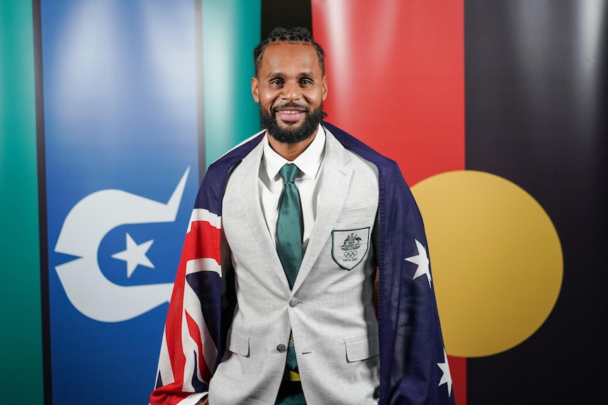 A male basketballer has the Australian flag over his shoulders.