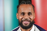 A male basketballer has the Australian flag over his shoulders.