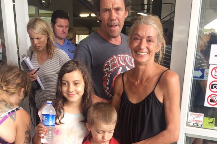 Sue Wokka stands with her two grandchildren in front of a door at the Pinjarra evacuation centre for the Waroona bushfire.