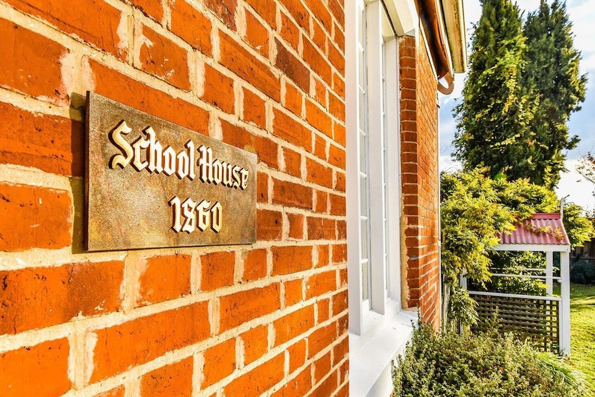 A sign saying "School House 1860" on red brick.