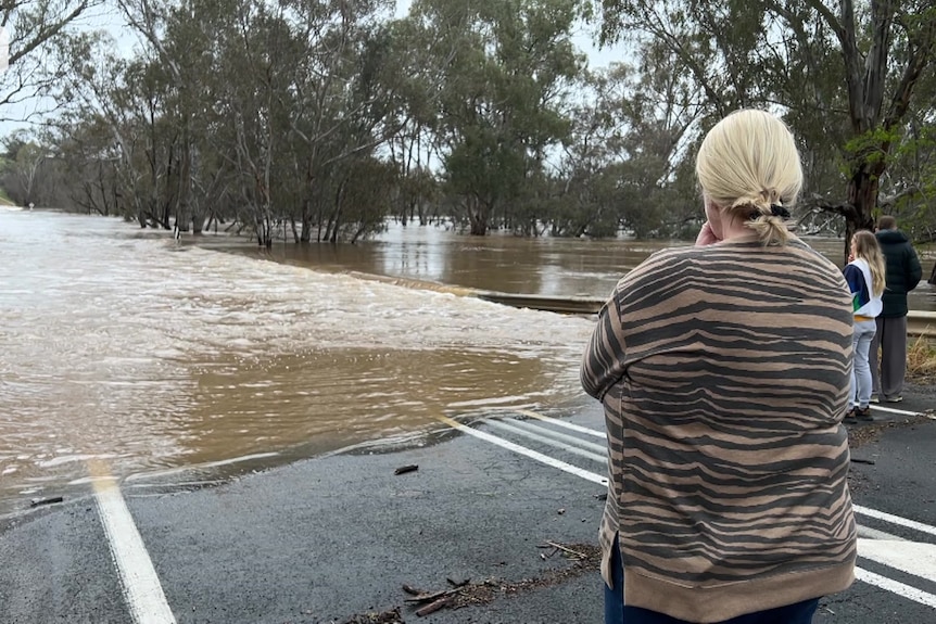 Locals stand at the water's edge on the roadway